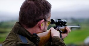 man wearing earplugs for shooting holding a gun